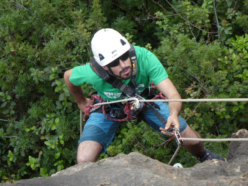 Trabajo en altura sobre roca con casco, arnés y cuerdas.