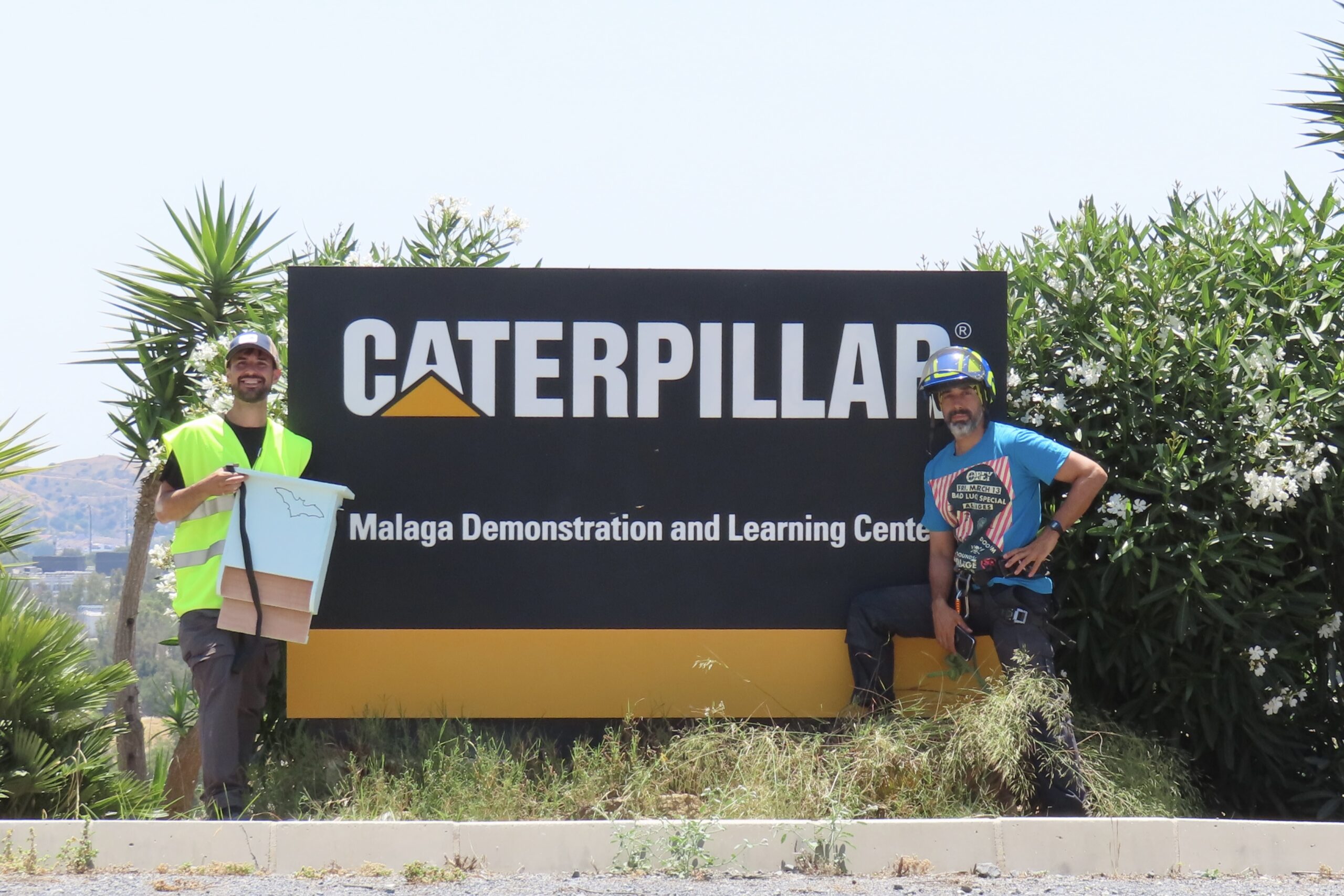 Antonio Moret y Pablo Mansilla junto al cartel de Caterpillar en Málaga.